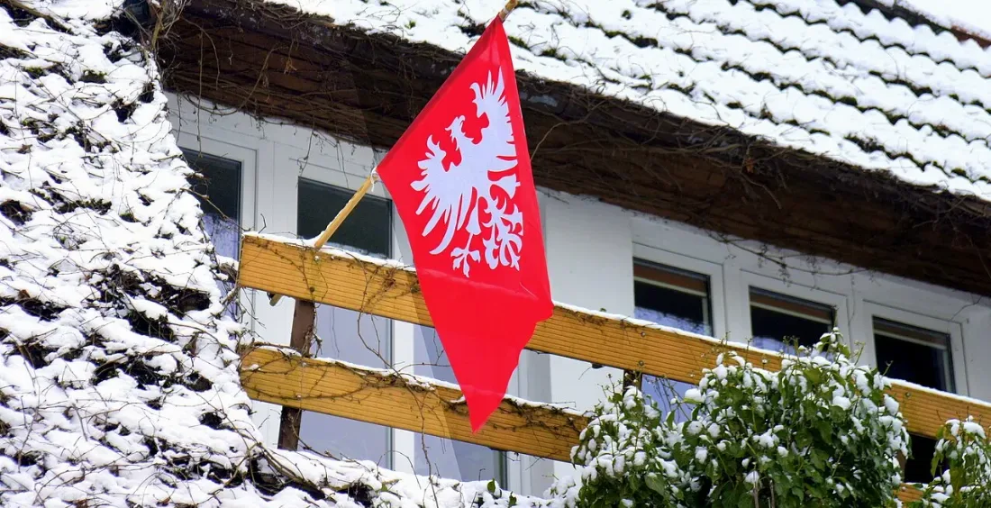 Flaga powstańców wielkopolskich z białym orłem wywieszona na domu